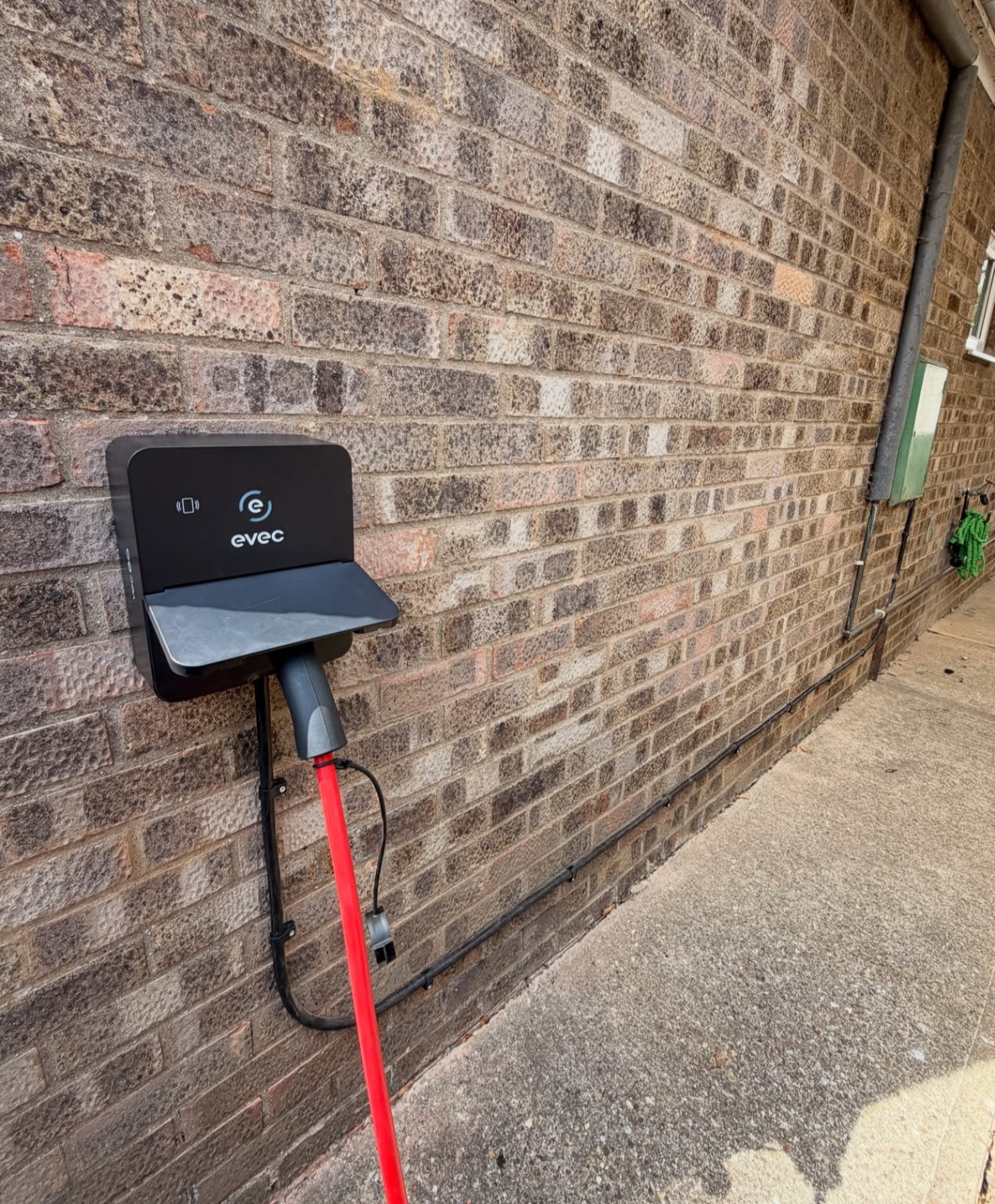 Evec EV charger installed on a brick commercial building