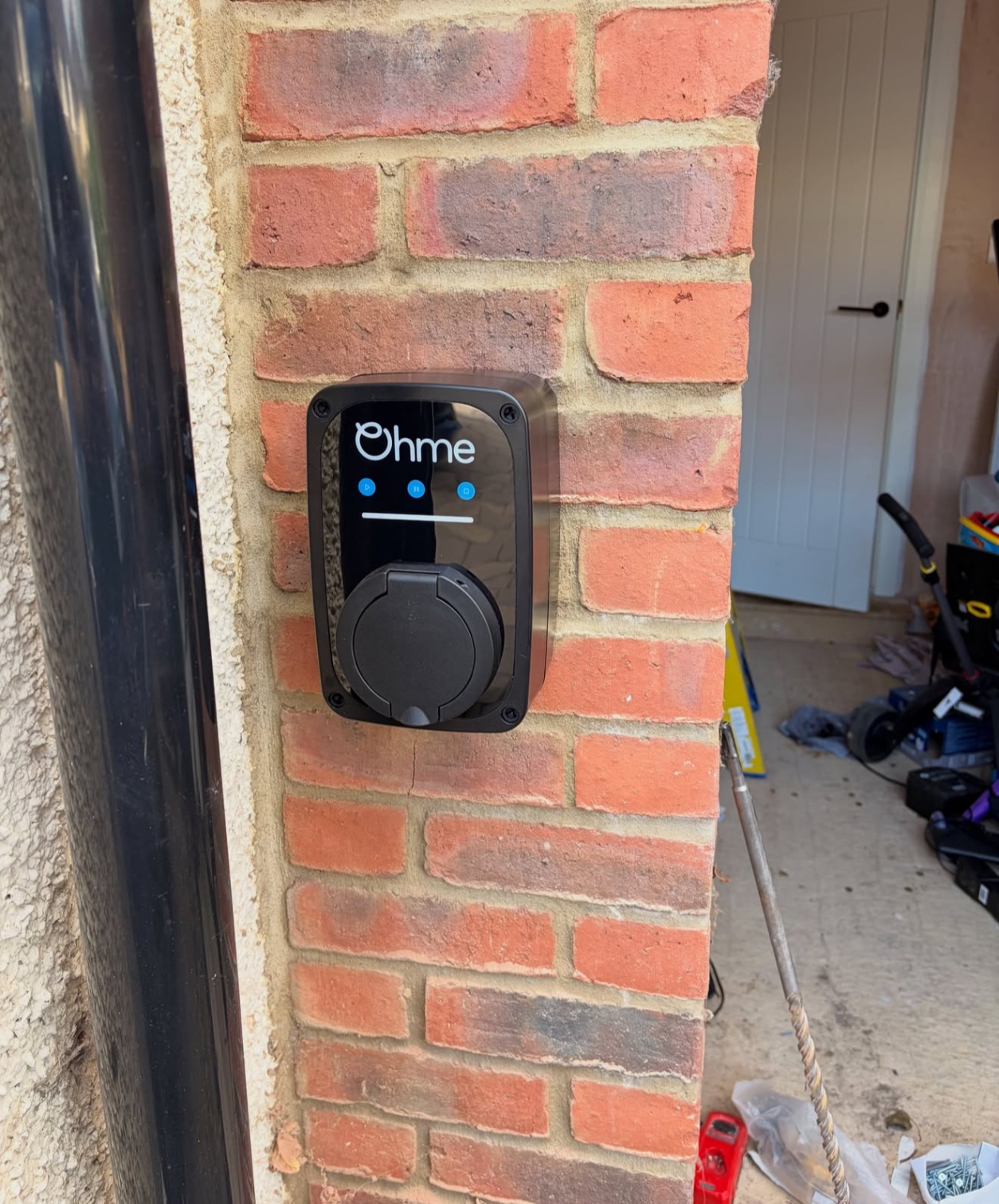 Socketed Ohme EV charger installed on a brick garage pillar