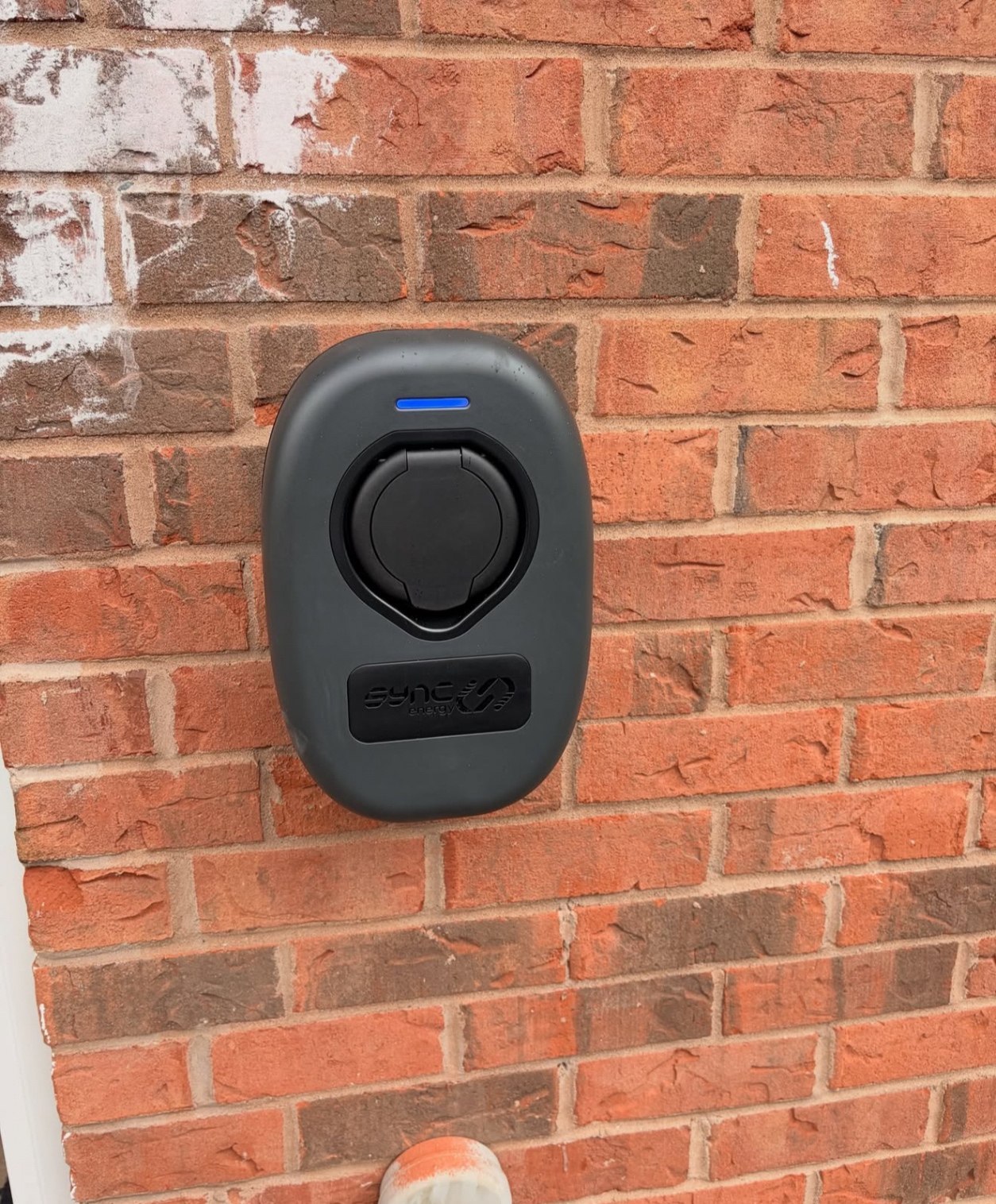 Socketed Sync EV charger installed on a red brick wall