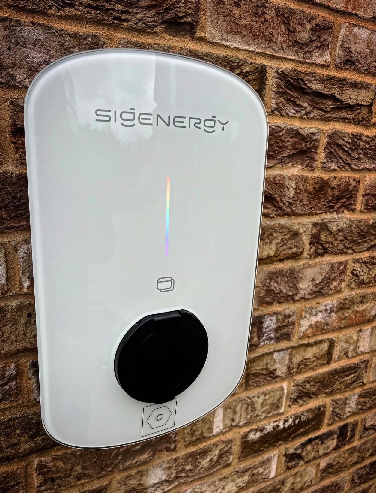 White Sigenergy EV charger installed on a brick wall